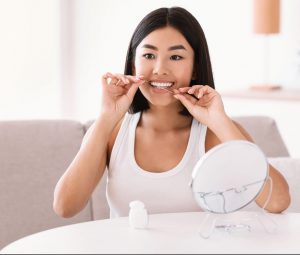 young-asian-lady-using-dental-floss-recording-vlog-DKWBCU3